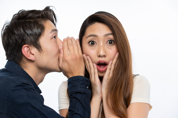 耳打ちする男性と驚く女性